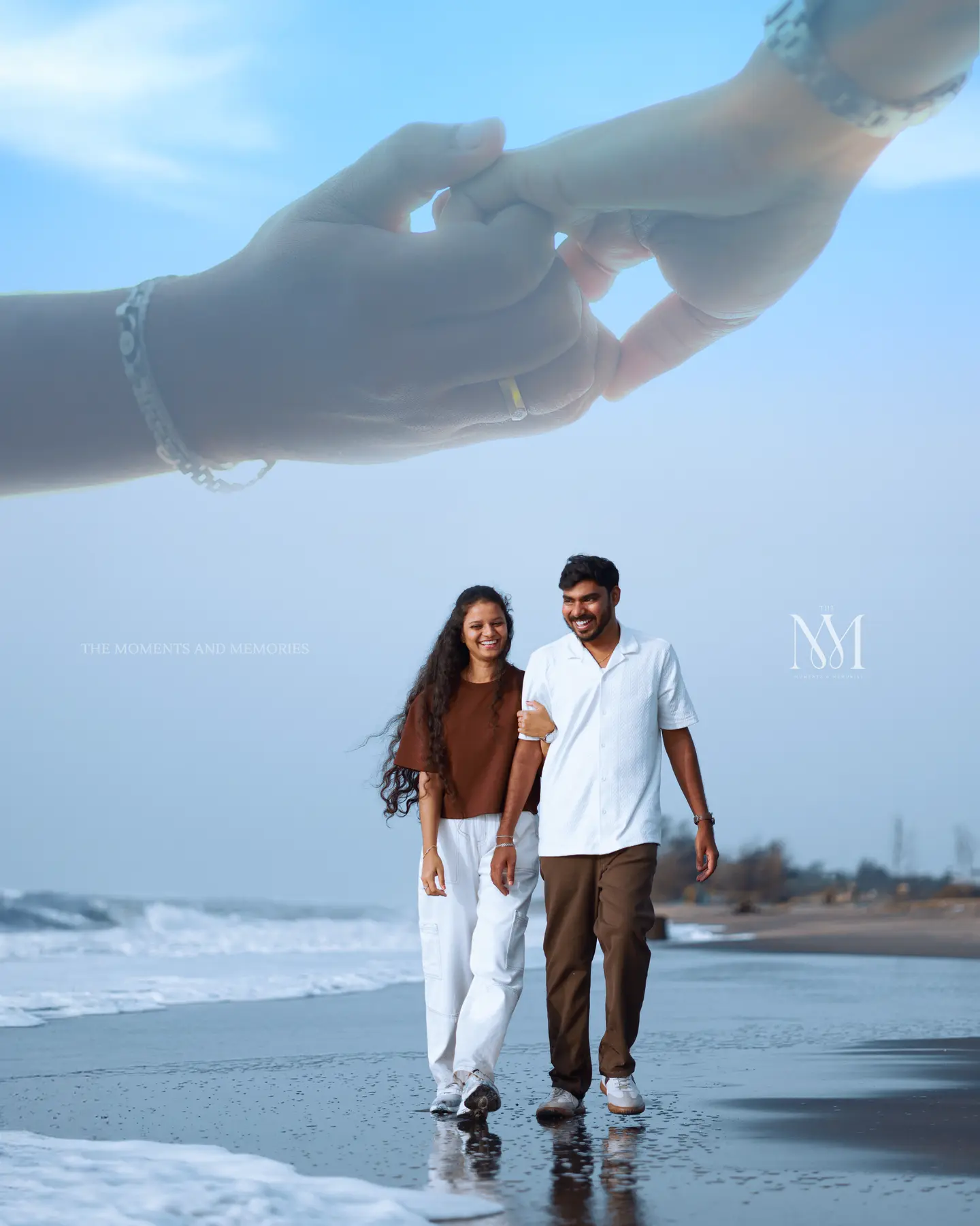 Couple walking on the beach beneath a heart-shaped hand gesture